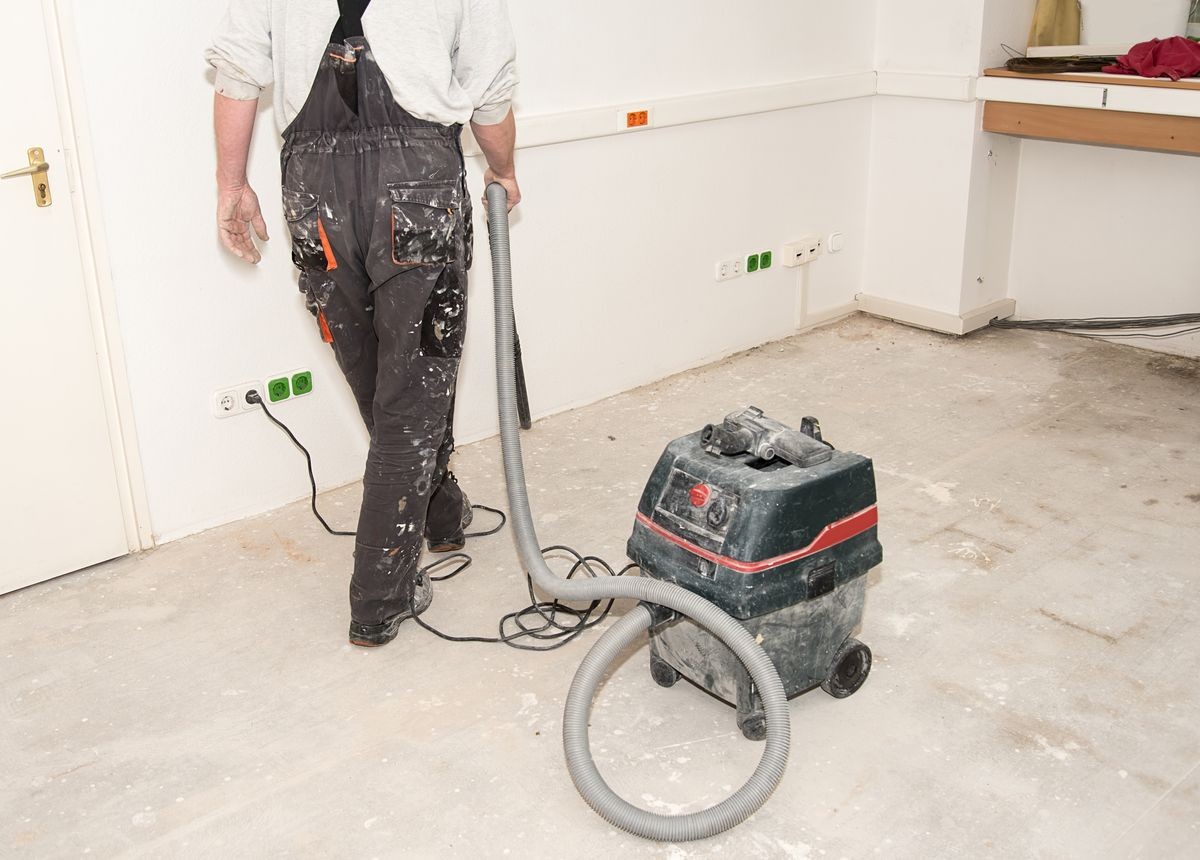 Worker man use vacuum cleaner in construction