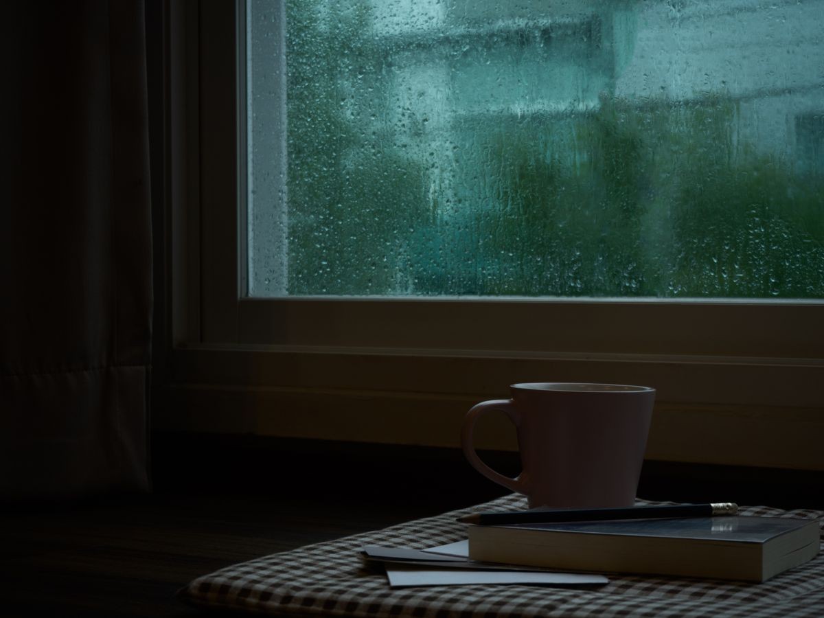 computer notebook next to a cup coffee on rainy day window background